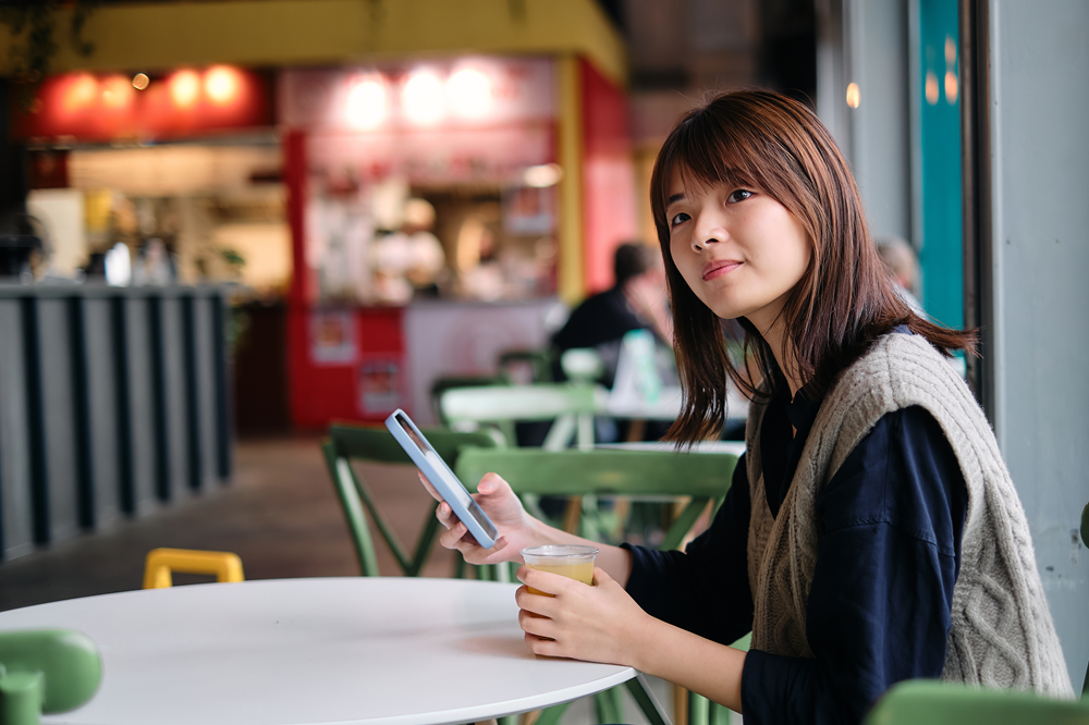 Mujer en cafetería con celular en la mano. mLearning.