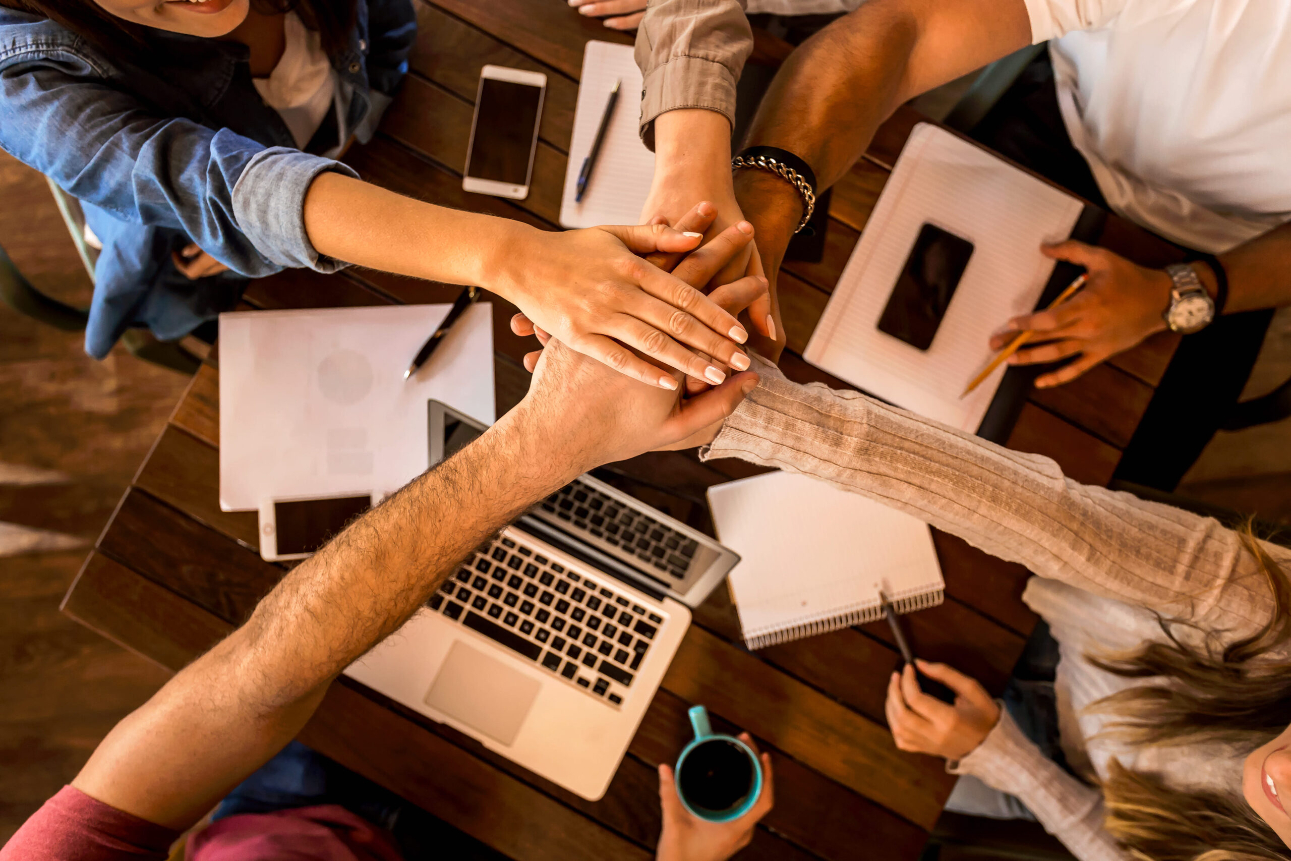 Grupo de amigos estudiando juntos, con las manos al centro